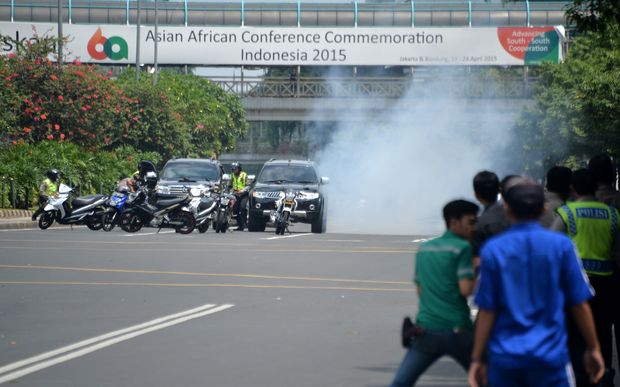 Police hide behind vehicles during an exchange of gunfire with suspects hiding near a Starbucks cafe when another blast hits