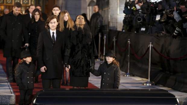 Celine Dion looks up to the sky as she stands with her children in front of casket of her late husband Rene Angelil