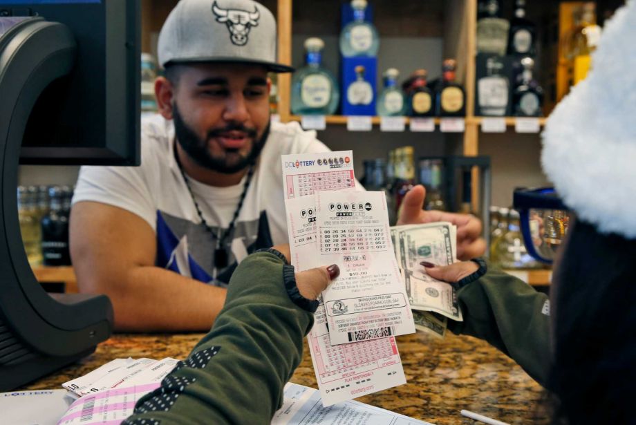 Samir Akhter the owner of Penn Branch Liquor exchanges money for Powerball tickets Saturday Jan. 9 2016 in Washington. Officials say it's increasingly likely that someone will win the $900 million Powerball jackpot which grew by $100 million just