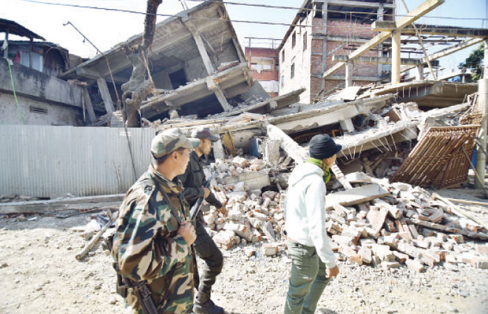 Security personel walk past a collapsed building following a 6.7 magnitude earthquake in Imphal Manipur India on Monday. — Reuters