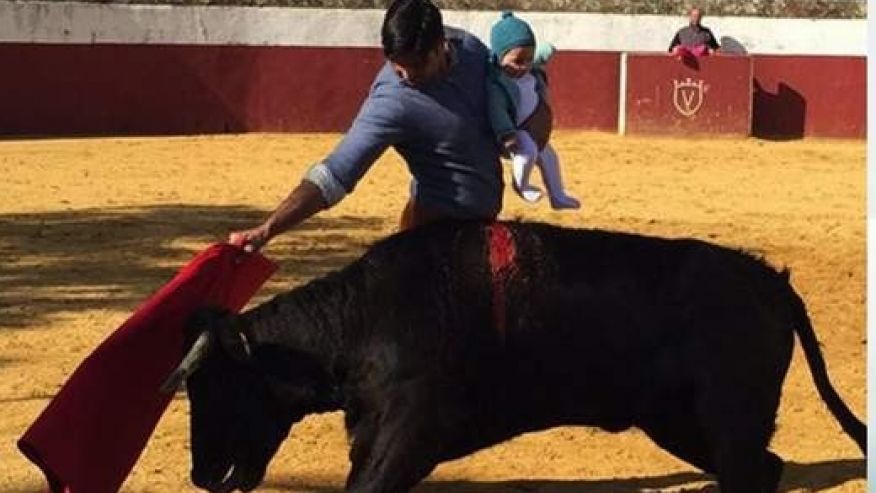 Spanish matador holds a baby in the bullfighting ring