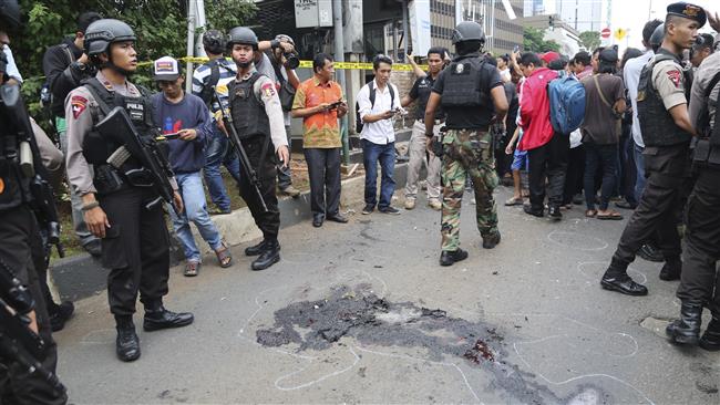 Police officers push back curious onlookers from the spot near a police post where an explosion went off in Jakarta Indonesia