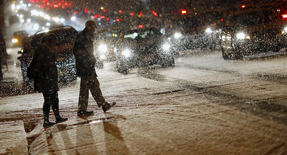 People cross a street as it snows in Washington