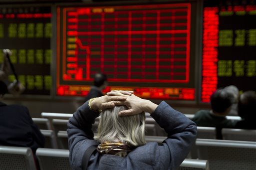 A woman reacts near a display board showing the plunge in the Shanghai Composite Index at a brokerage in Beijing China Thursday Jan. 7 2016. Chinese stocks nosedived on Thursday triggering the second daylong trading halt of the week and sending other