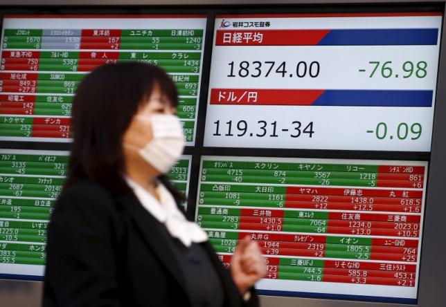 A woman walks past a screen displaying market data and exchange rates between the Japanese yen and the U.S. dollar outside a brokerage in Tokyo Japan