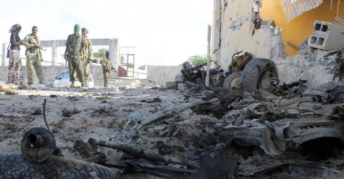 Somali soldiers stand next to the site where Al Shebab militants carried out a suicide attack against a military intelligence base in Mogadishu