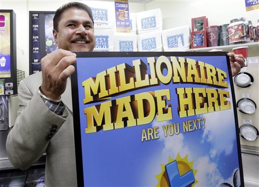 Balbir Atwal the owner of a 7 Eleven store that sold a winning Powerball lottery ticket holds up a Millionaire Made Here sign at his store in Chino Hills on Thursday