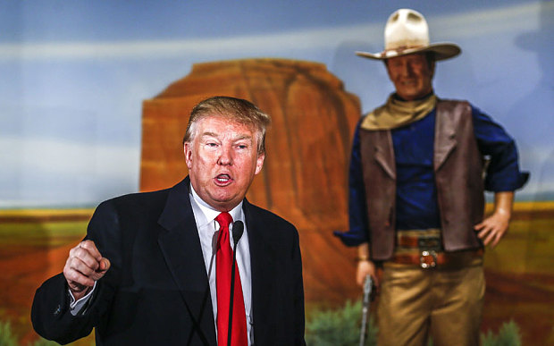 Republican presidential candidate Donald Trump speaks in front of a statue of actor John Wayne after receiving the endorsement of Wayne's daughter Aissa Wayne