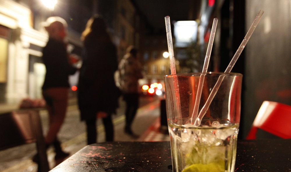 Two young women smoke outside a bar in the central London area of Soho