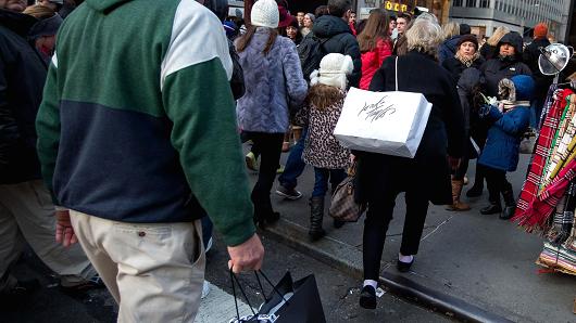 Pedestrians carry shopping bags while walking along 5th Avenue in New York