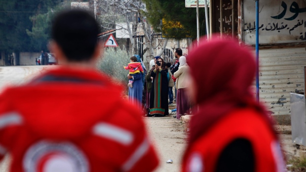 Members of the Syrian Red Cross stand near aid vehicles loaded with food and other supplies that entered the besieged Syria town of Madaya northwest of Damascus earlier this week