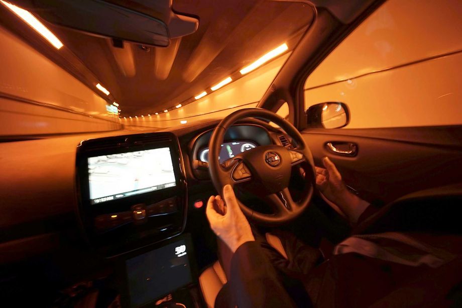 Nissan Motor Co. General Manager Tetsuya Iijima takeshis hands off of the steering wheel of a self-driving prototype vehicle during a test drive in Tokyo. While self-driving cars of tomorrow already are being tested