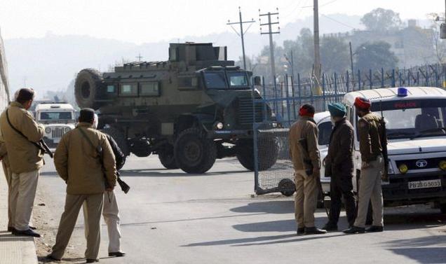 Security men standing guard as an armored vehicle moves near the Indian Air Force base that was attacked by militants in Pathankot in Punjab on Saturday