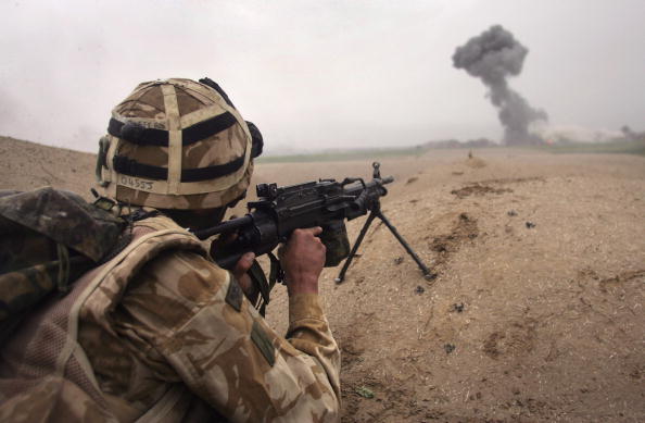 KAJAKI AFGHANISTAN- MARCH 18 British commando Lee Oliver fires at Taliban only 400 meters away as a plume of smoke rises from an airstrike during a sunrise attack on Taliban positions