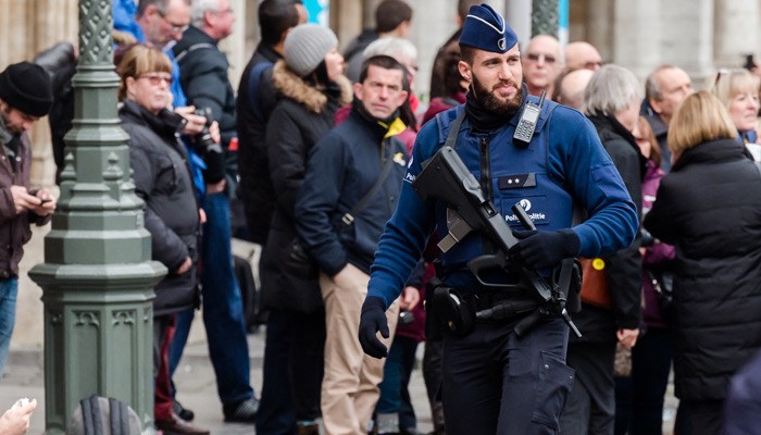 An armed police man patrols at the Grand Place in Brussels on Tuesday. Two people have been arrested in Belgium on suspicion of planning attacks in Brussels during the holidays the federal prosecutor's office said