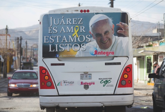 A bus drives through in Ciudad Juarez Mexico with an ad showing Pope Francis and saying “Juarez is Love. We are Ready”