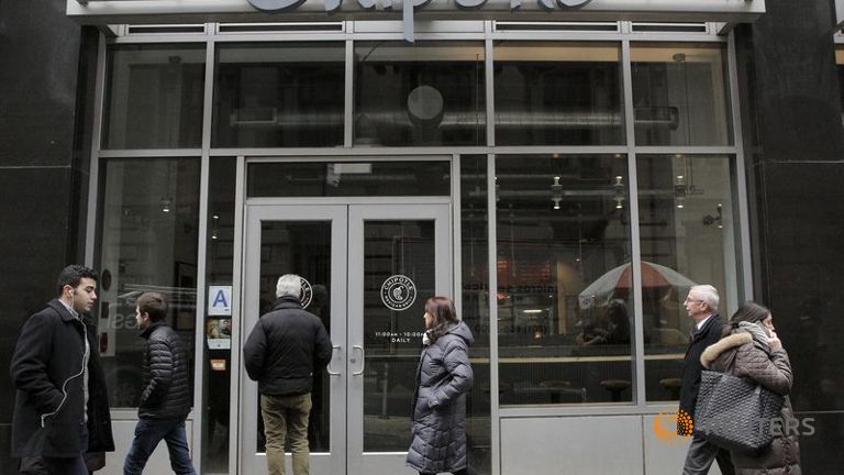 A customer reads a sign posted on the door of a Chipotle Mexican Grill in New York