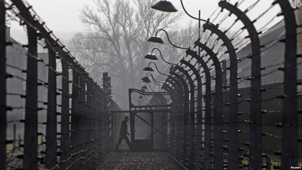 A visitor walks between electric barbed-wired fences at the Auschwitz Birkenau memorial and former concentration camp