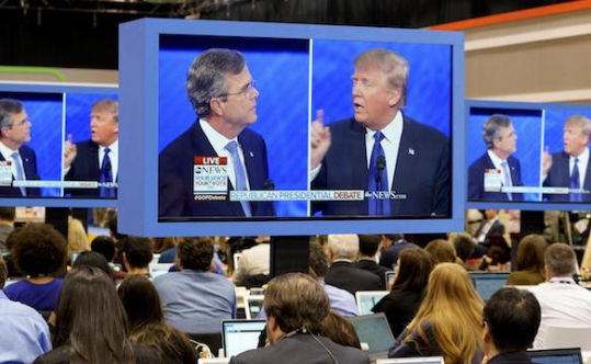 Republican presidential candidate businessman Donald Trump right puts his finger in front of his mouth and tells former Governor Jeb Bush left to'be quiet as journalists watch the debate on monitors on Feb. 6