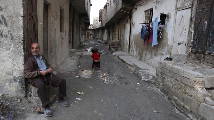 An elderly man holds beads as he sits at a street in the rebel-held neighborhood of Tishreen after a ceasefire that went into effect in Damascus