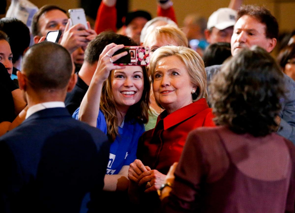 Democratic presidential candidate Hillary Clinton stands with a supporter taking a selfie