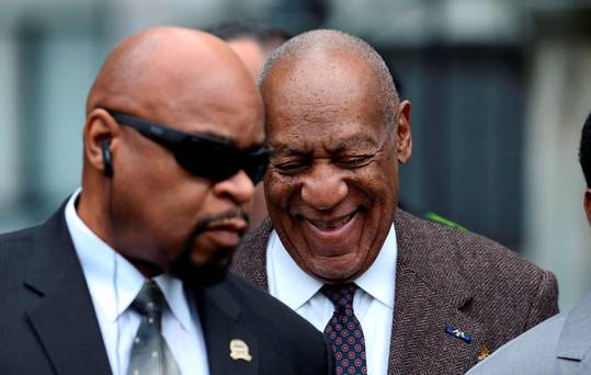 Bill Cosby right smiles as he arrives for a court appearance yesterday in Norristown Pennsylvania