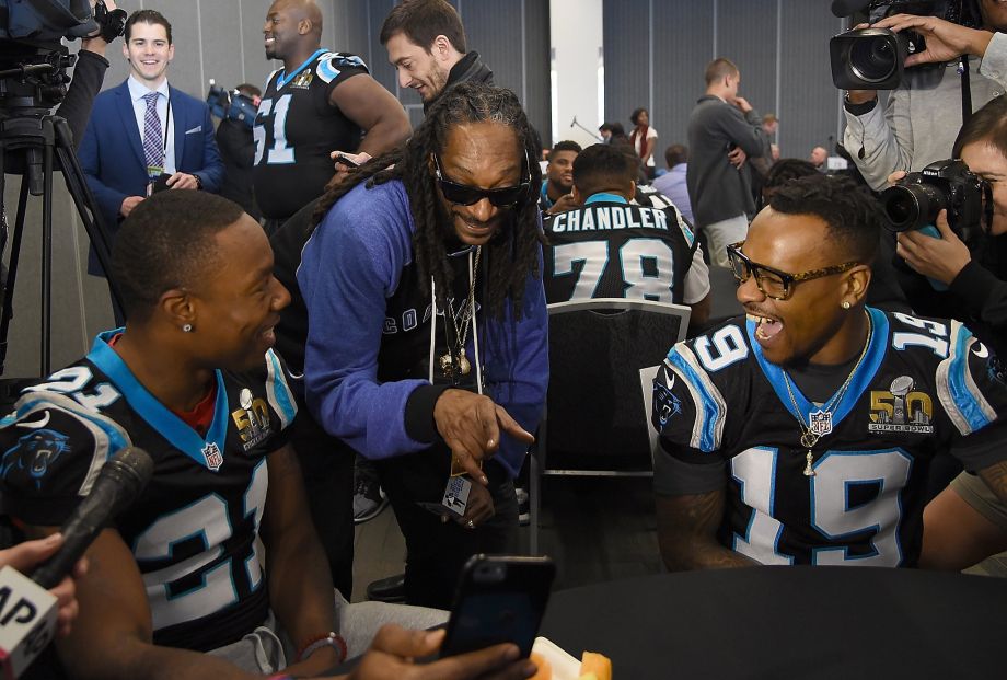 Rapper and actor Snoop Dogg talks with Teddy Williams and Ted Ginn Jr. of the Carolina Panthers during media availability at the San Jose Convention Center