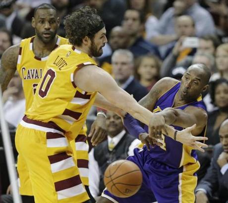 Los Angeles Lakers&apos Kobe Bryant right passes around Cleveland’s Kevin Love in the first half of an NBA basketball game as Le Bron James watches Wednesday Feb. 10 2016 in Cleveland