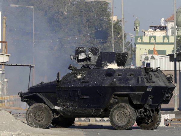 A police armored vehicle splattered with paint bombs fires tear gas toward Bahraini anti-government protesters during clashes in Sitra Bahrain on Sunday Feb. 14 2016. Hundreds of Bahraini youths shouting anti-government slogans have taken to the stree