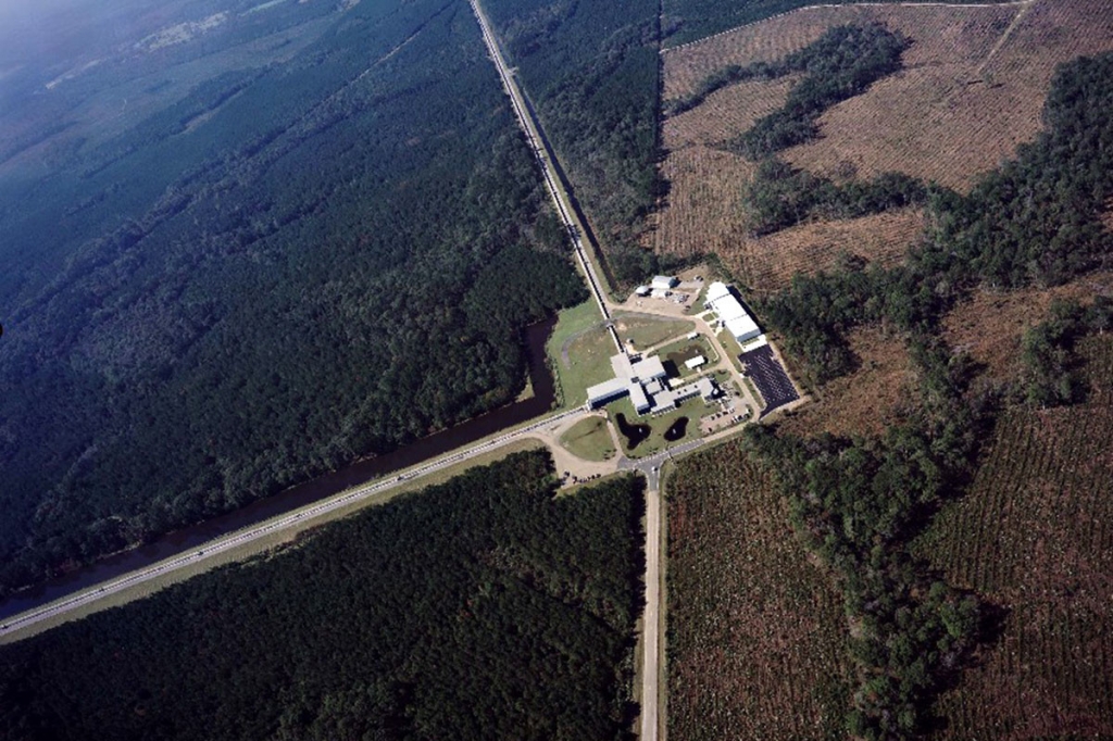 An aerial view of the LIGO Observatory. Medium size official looking building surrounded by woods