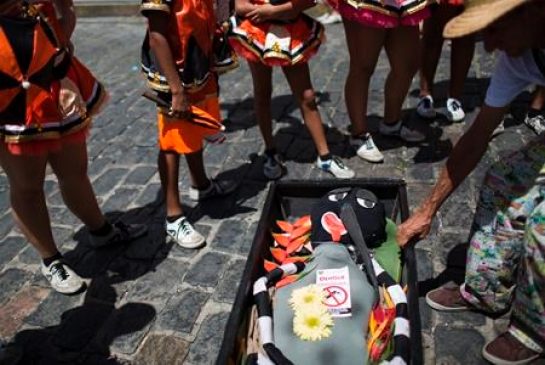 A reveler drags a coffin containing an Aedes aegypti mosquito puppet during the