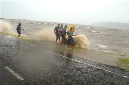 People are splashed by a wave whipped up by the encroaching cyclone Winston in Labasa Fiji Saturday Feb. 20 2016. The Pacific island nation of Fiji is hunkering down as a formidable cyclone with winds of 300 kilometers per hour approaches