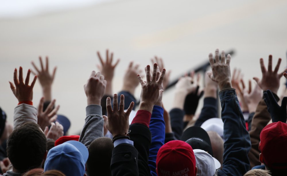 Audience members reach for free items being thrown during Republican presidential candidate Donald Trump’s campaign event at Dubuque Regional Airport on Saturday in Dubuque Iowa