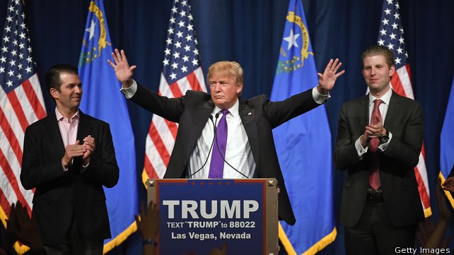 Donald Trump speaks as his sons Donald Trump Jr and Eric Trump look on during the caucus