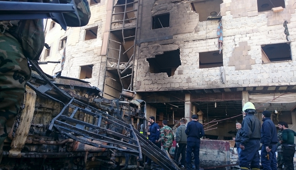 Residents and soldiers loyal to Syria's President Bashar al Assad inspect damage after a suicide attack in Sayeda Zeinab a district of southern Damascus