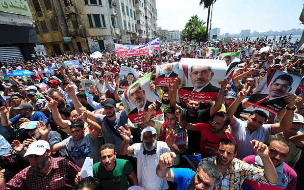 Egyptian president Mohamed Morsi loyalists raise up posters of him shouting slogans during a march