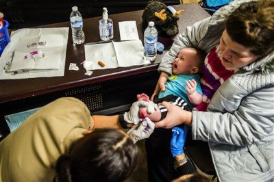 Flint resident Sheree Walker holds onto her 5-month-old son Ryder Walker on Feb. 8 as to U.S. Public Health Service health officials prick his foot with a needle collecting blood for a free lead test on at Carriage Town Ministries in Flint Mich. Moli