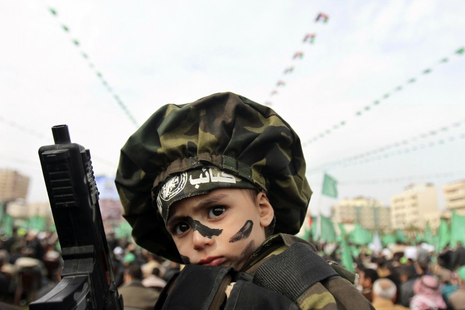 A boy wearing an Al Qassam Brigades headband is carried by his father during a Hamas rally in Gaza City