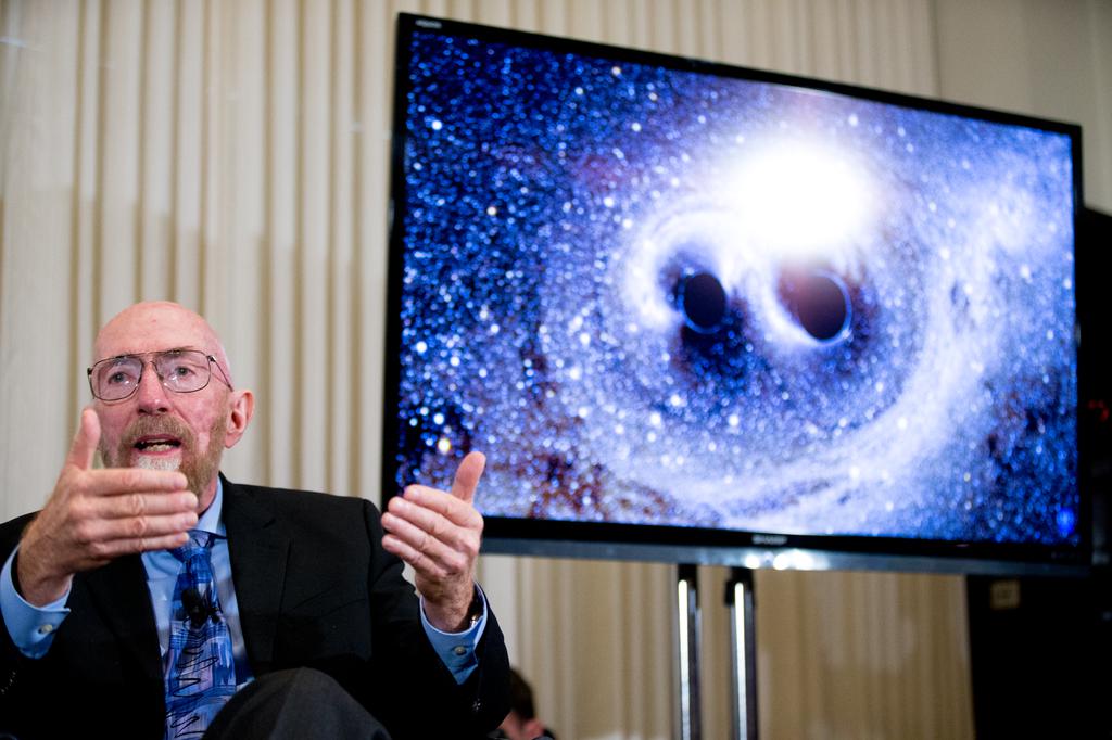 Laser Interferometer Gravitational Wave Observatory Co Founder Kip Thorne speaks next to a visual of gravitational waves from two converging black holes right during a news conference at the National Press Club in Washington Thursday Feb. 11 2