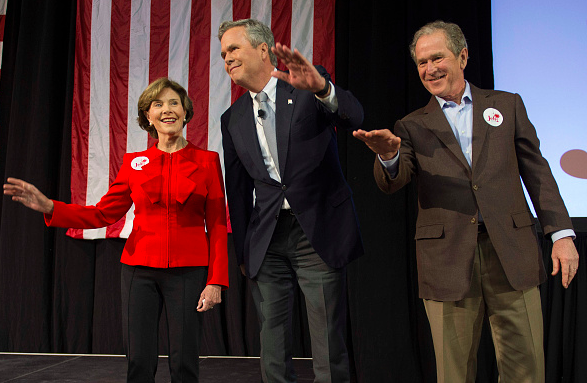 Former US President George W. Bush waves with his wife Laura as he stands with his brother and Republican presidential candidate Jeb Bush during a campaign rally in Charleston South Carolina