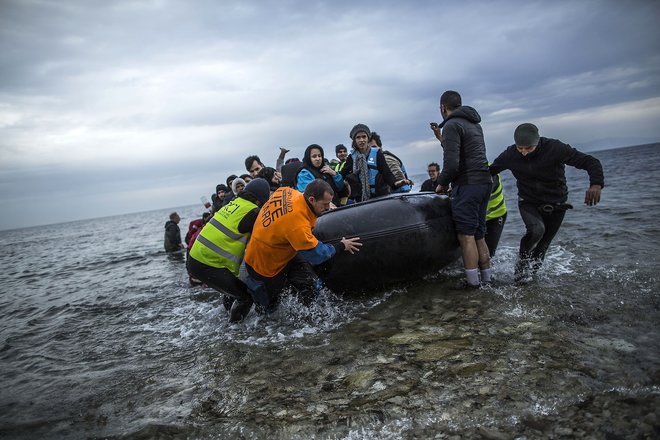 Refugees and migrants are helped by volunteers as they arrive on a dinghy from the Turkish coast to Mytilene Lesbos island Greece on Wednesday Feb. 24 2016. The International Organization for Migration said more than 102,500 people had crossed into G