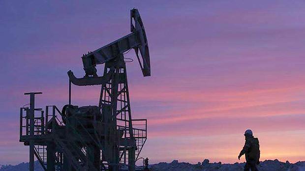 A worker walking past a pump jack on an oil field owned by Bashneft company near the village of Nikolo-Berezovka northwest from Ufa Bashkortostan Russia