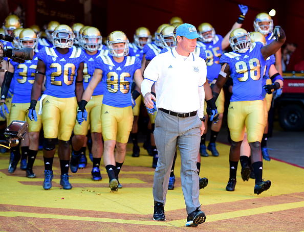 Head coach Jim Mora of the UCLA Bruins leads his team on to the field for a game against the USC Trojans