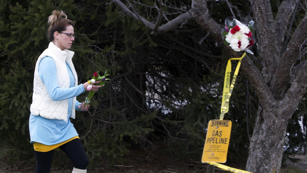 A woman places flowers at a Cracker Barrel restaurant where people were gunned down in the parking lot amid an hours-long shooting spree in Kalamazoo Mich