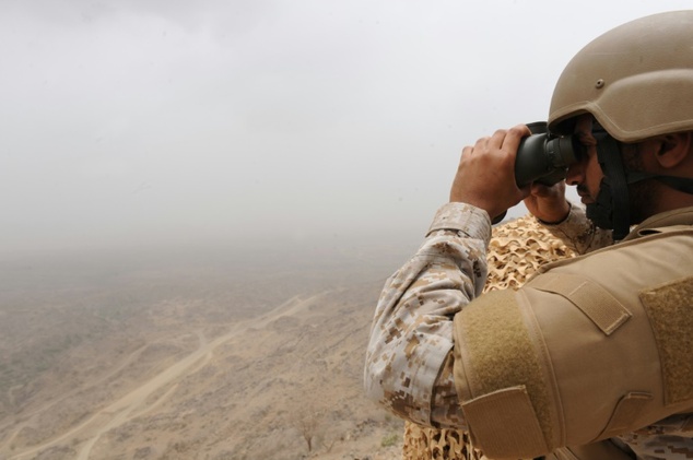 A Saudi soldier looks through binoculars from a position at al Dokhan mountain on the Saudi Yemeni border in southwestern Saudi Arabia