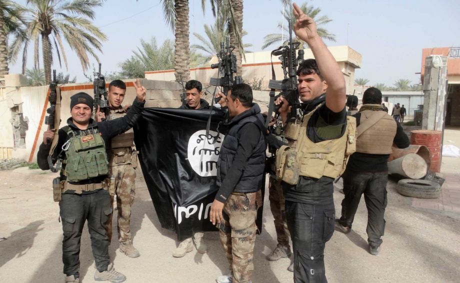 Iraqi security forces celebrate as they hold a flag of the Islamic State group they captured in Ramadi 70 miles west of Baghdad Iraq. Iraqi security forces and the U.S.-led coalition