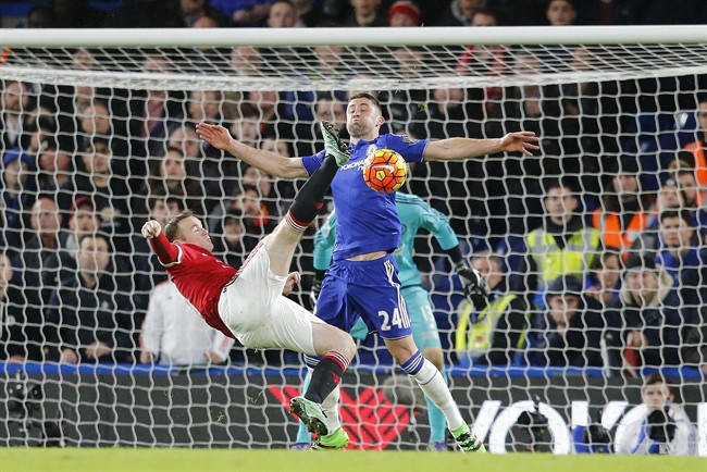 Manchester United's captain Wayne Rooney gets in a shot despite the challenge of Chelsea's Gary Cahill during the English Premier League soccer match between Chelsea and Manchester United at Stamford Bridge stadium in London Sunday Feb. 7 2016. (AP Pho