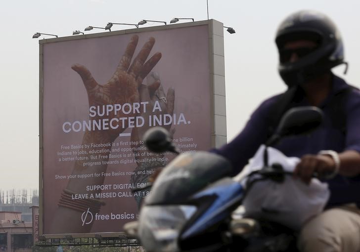 A motorist rides past a billboard displaying Facebook's Free Basics initiative in Mumbai