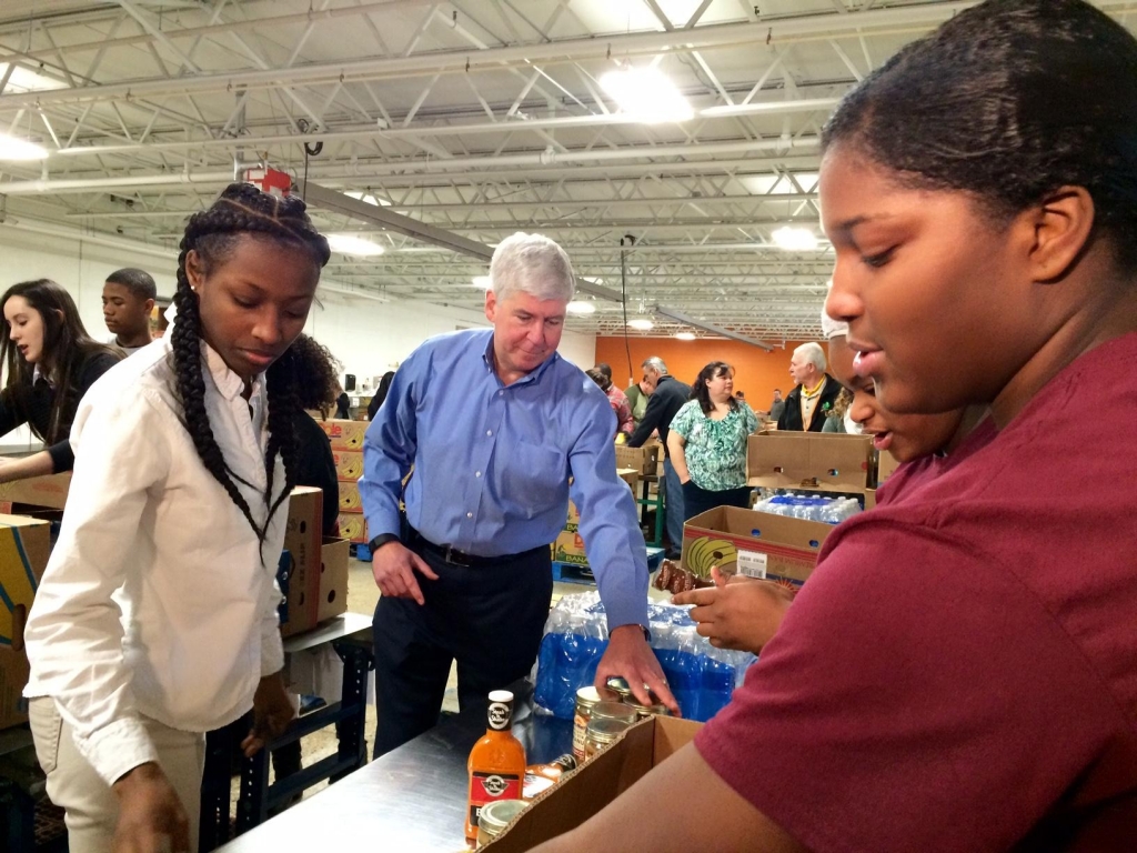 Gov. Snyder sorts cans and boxes of food alongside students from Detroit's Renaissance High School who were at the food bank for a day of service