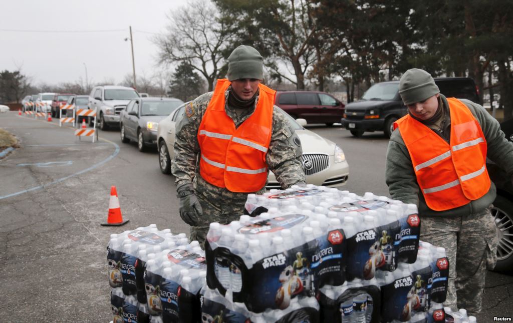 Michigan National Guard members distribute water to a line of residents in their cars in Flint Michigan Jan. 21 2016